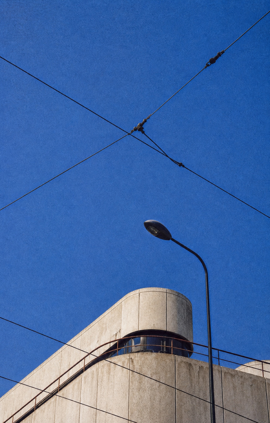 Modernistyczna architektura na tle niebieskiego nieba i łódzkich przewodów tramwajowych